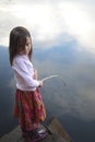 Portrait of a girl fishing in lake reflecting the sky Royalty Free Stock Photo