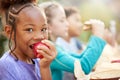 Portrait Of Girl With Friends Eating Healthy Picnic At Outdoor Table In Countryside