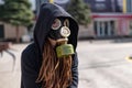 Portrait of a girl in a gas mask and a black mantle