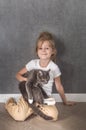 Portrait of a girl with a gray cat with yellow eyes in her hands on a gray background. Vertical photo Royalty Free Stock Photo