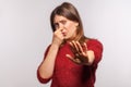 Portrait of girl grimacing in disgust and pinching her nose, showing stop hand gesture confused by bad breath