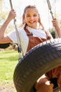 Portrait Of Girl Having Fun On Tyre Swing In Garden At Home Royalty Free Stock Photo