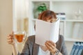 Portrait of a girl holding an open book to her face in one hand and a cup of tea in the other against the background of Royalty Free Stock Photo