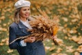 Portrait of a Girl in a jacket and birette with an autumn bouquet in an autumn park