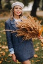 Portrait of a Girl in a jacket and birette with an autumn bouquet in an autumn park