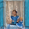 Portrait of girl kid tailor sew making doll's clothes on a children's sewing machine in the window of an old Royalty Free Stock Photo