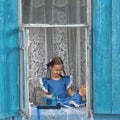 Portrait of girl kid tailor sew making doll's clothes on a children's sewing machine in the window of an old Royalty Free Stock Photo