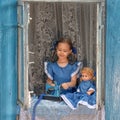 Portrait of girl kid tailor sew making doll& x27;s clothes on a children& x27;s sewing machine in the window of an old Royalty Free Stock Photo