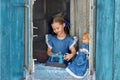 Portrait of girl kid tailor sew making doll& x27;s clothes on a children& x27;s sewing machine in the window of an old Royalty Free Stock Photo