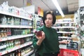 Portrait of a girl looking at a bottle of wine in her hand during shopping. Shopping for alcohol in a supermarket. Royalty Free Stock Photo