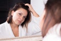 Portrait of a girl looking at herself in the reflection of the mirror, with disheveled hair. Greasy, dirty hair Royalty Free Stock Photo