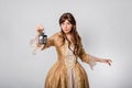 Portrait of a girl in a lush golden rococo dress posing standing with a lamp in her hands isolated on a white background