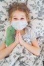 Top view. girl lying in bed medical mask dinosaur Royalty Free Stock Photo