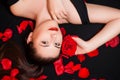 Portrait of a girl lying on a black background and rose petals. Royalty Free Stock Photo