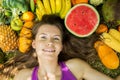 Portrait of a girl lying on the grass with fruits and vegetables