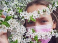 Portrait of a girl in a medical mask with a flowering tree.