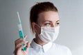 Portrait of a girl in a medical mask. Holding a syringe in her hand. Close up Royalty Free Stock Photo