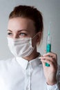 Portrait of a girl in a medical mask. Holding a syringe in her hand. Close up Royalty Free Stock Photo