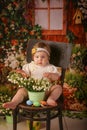 Portrait girl one year old shooting in studio sitting on wooden chair snowdrops background flowers Royalty Free Stock Photo