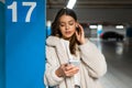 Portrait of girl with phone in hands who correcting the earphone in her ear. Young fashionable woman with phone and headphones Royalty Free Stock Photo