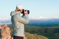 Portrait of a girl photographer in a cap on nature photographing on her digital mirror camera. Back view Royalty Free Stock Photo