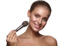 Portrait of a girl with pure and healthy glowing smooth skin, who is applying daily makeup on her face using a brush in her hand Royalty Free Stock Photo