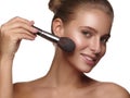 Portrait of a girl with pure and healthy glowing smooth skin, who is applying daily makeup on her face using a brush in her hand Royalty Free Stock Photo