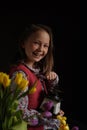 Portrait of a girl in rural clothes and a retro coffee grinder in her hands on a dark background. Medieval little girl.