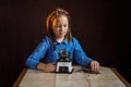 Portrait of a girl in rural clothes and a retro coffee grinder in her hands on a dark background. Medieval little girl.
