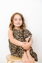 Portrait of a girl, she sits hugging her knees in a leopard print dress Royalty Free Stock Photo