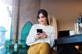 Portrait of girl sitting cafe, using smartphone. Young woman reads text message on phone while sitting coffee shop. Lifestyle Royalty Free Stock Photo