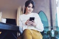 Portrait of girl sitting cafe, using smartphone. Young woman reads text message on phone while sitting coffee shop. Lifestyle Royalty Free Stock Photo