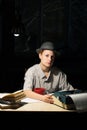 Portrait of a girl sitting at a table with a typewriter and books, think about the idea at night