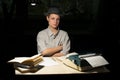 Portrait of a girl sitting at a table with a typewriter and books, think about the idea at night