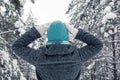 portrait of a girl stands in a beautiful winter snowy forest, raising her hands to her head, examines the trees. Royalty Free Stock Photo