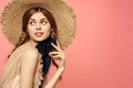 Portrait of a girl in a straw hat on a pink background emotions close-up beautiful face model pigtails