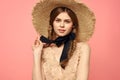 Portrait of a girl in a straw hat on a pink background emotions close-up beautiful face model pigtails