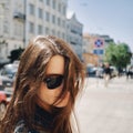 Portrait of a girl with sunglasses against the background of the city with flying hair in the wind Royalty Free Stock Photo