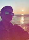 Portrait girl in sunglasses with a short haircut against the sunset. reflection of palm trees in glasses Royalty Free Stock Photo
