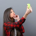 Portrait of a girl taking selfie with cellphone against gray background Royalty Free Stock Photo