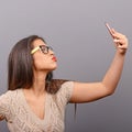 Portrait of a girl taking selfie with cellphone against gray background Royalty Free Stock Photo