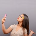 Portrait of a girl taking selfie with cellphone against gray background Royalty Free Stock Photo