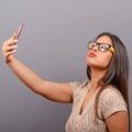 Portrait of a girl taking selfie with cellphone against gray background Royalty Free Stock Photo