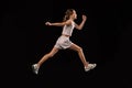 Full-length side view portrait of girl, teenager, professional runner training isolated over black background