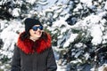 Portrait of a girl teenager wearing black and red coat standing among fir trees covered with snow at the winter park. Young woman Royalty Free Stock Photo