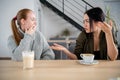 Portrait of a girl telling secrets to her amazed friend sitting at a cafe during lunch break Royalty Free Stock Photo