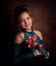 Portrait of a girl of ten years in a green dress with flowers of red roses. The girl is holding a bouquet and smiling. Royalty Free Stock Photo