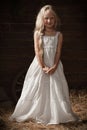 Portrait of a girl in a white sundress on the hay in the barn Royalty Free Stock Photo