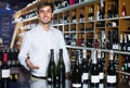 Portrait of glad male customer taking bottle of wine in store