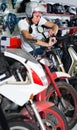 Portrait of glad male in helmet on motorbike in the store